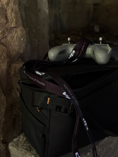 Radiocommande DJI posée sur le sac de transport du matériel, rangée contre un mur de pierre en fin de tournage.
