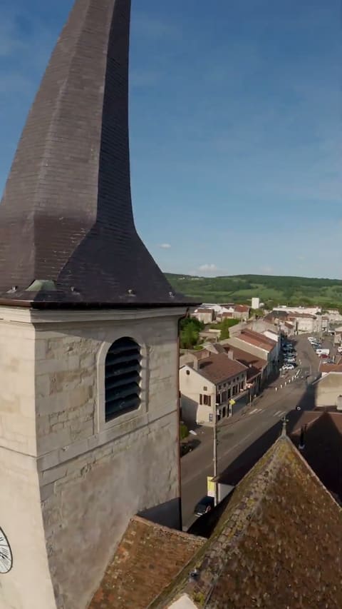 Passage du drone le long du clocher d'un village, la rue principale et les toits en contrebas.